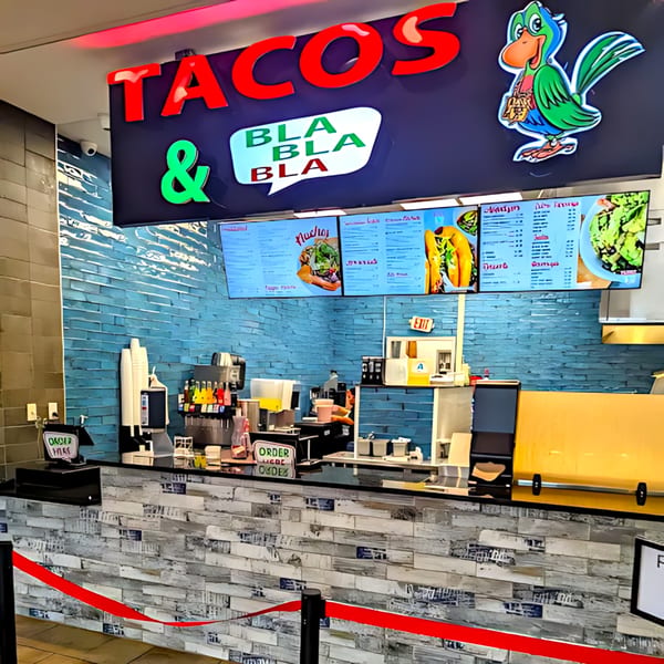 Tacos & Bla Bla Bla restaurant counter with menu screens, soda fountain, and order signs.