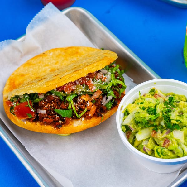 A Tacos & Bla Bla Bla gordita with meat, lettuce, and cheese, served with guacamole.